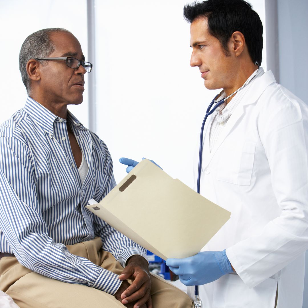 White male doctor with folder in hand having a discussion with black male patient